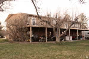 Back of house with a hot tub, a deck, and a lawn