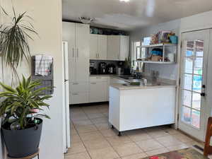 Kitchen with a wealth of natural light, white cabinetry, and light tile patterned floors