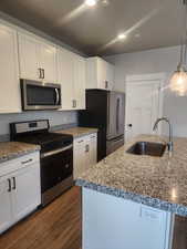 Kitchen featuring sink, white cabinetry, stainless steel appliances, and hanging light fixtures