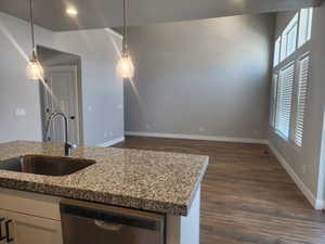 Kitchen with dishwasher, pendant lighting, stone countertops, and sink