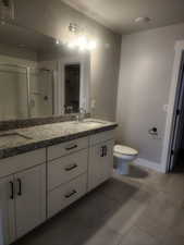 Bathroom with tile patterned floors, toilet, vanity, and walk in shower