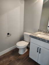 Bathroom with hardwood / wood-style floors, vanity, and toilet