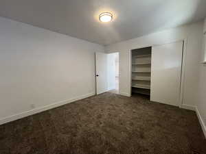 Unfurnished bedroom with dark carpet and a closet