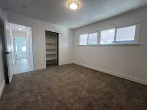 Unfurnished bedroom featuring carpet, a textured ceiling, and a closet