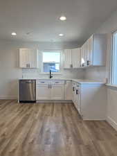 Kitchen with white cabinetry, dishwasher, hardwood / wood-style floors, and sink