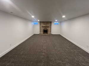 Basement featuring a fireplace, plenty of natural light, and dark colored carpet