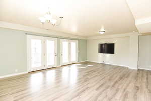 Unfurnished living room featuring a chandelier and light hardwood / wood-style flooring