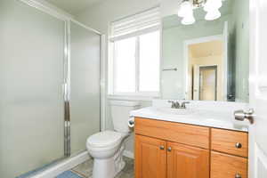 Bathroom with tile patterned floors, vanity, a shower with shower door, and toilet