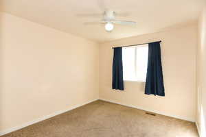 Carpeted empty room featuring ceiling fan