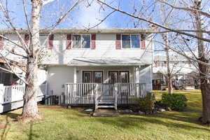 View of front of property with a deck and a front lawn