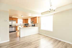 Kitchen with kitchen peninsula, a wealth of natural light, light hardwood / wood-style flooring, and appliances with stainless steel finishes