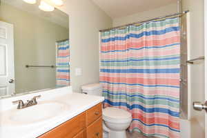 Bathroom featuring a shower with shower curtain, vanity, toilet, and tile patterned floors