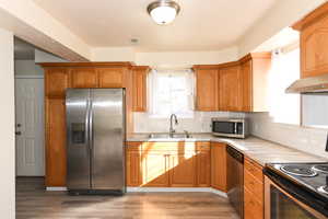 Kitchen featuring stainless steel appliances, tasteful backsplash, light hardwood / wood-style floors, and sink