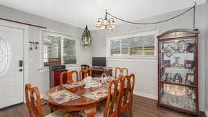 Dining space with dark hardwood / wood-style flooring and a chandelier