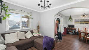 Living room featuring dark hardwood / wood-style flooring, crown molding, and an inviting chandelier