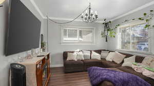 Living room featuring a chandelier, dark wood-type flooring, and ornamental molding