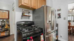 Kitchen featuring stainless steel fridge, dark hardwood / wood-style floors, black gas range oven, and an inviting chandelier