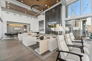 Living room with hardwood / wood-style flooring, a towering ceiling, and wooden ceiling