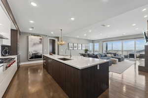 Kitchen with dark hardwood / wood-style flooring, dark brown cabinets, sink, a center island with sink, and a chandelier