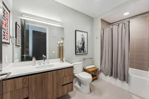 Full bathroom with tile patterned flooring, vanity, shower / tub combo, and toilet