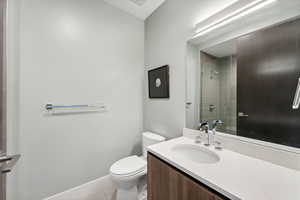 Bathroom with tile patterned flooring, vanity, toilet, and a tile shower