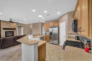 Kitchen with a kitchen island with sink, sink, ceiling fan, light tile patterned floors, and stainless steel appliances