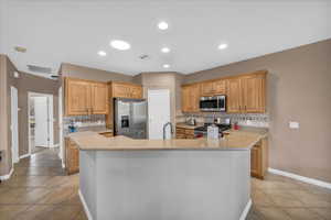 Kitchen with stainless steel appliances, tasteful backsplash, and an island with sink