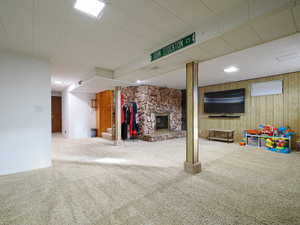 Basement featuring carpet floors, a fireplace, and wooden walls