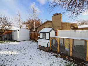 Snow covered property featuring a storage unit