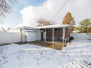 Snow covered back of property featuring a storage shed