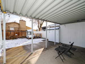 Snow covered patio featuring a storage unit