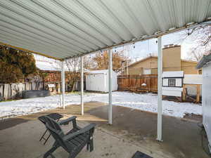 Snow covered patio featuring a storage unit