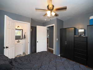 Bedroom featuring ensuite bath, ceiling fan, sink, and a textured ceiling