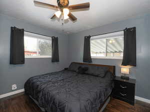 Bedroom with multiple windows, a textured ceiling, ceiling fan, and dark wood-type flooring