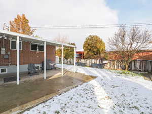 Yard layered in snow with a patio area