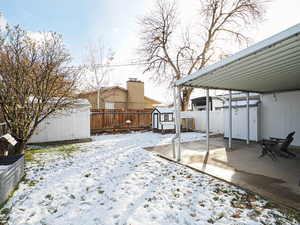 Snowy yard with a patio area and a storage unit