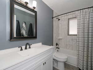 Full bathroom with vanity, shower / tub combo, a textured ceiling, and toilet