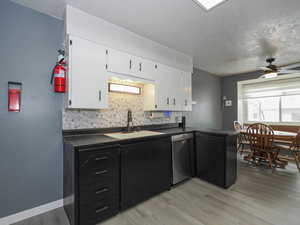 Kitchen featuring light hardwood / wood-style floors, white cabinetry, stainless steel dishwasher, and sink