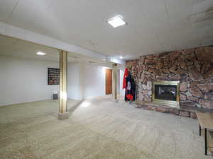 Basement featuring carpet and a stone fireplace