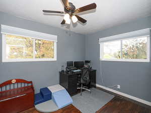 Office space with a textured ceiling, ceiling fan, and dark wood-type flooring