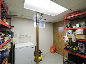 Basement featuring a paneled ceiling and fridge