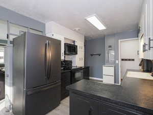 Kitchen featuring white cabinets, sink, light wood-type flooring, a textured ceiling, and stainless steel appliances