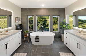 Bathroom with tile patterned floors, vanity, a tub to relax in, and tile walls