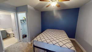 Carpeted bedroom with connected bathroom, ceiling fan, a spacious closet, a textured ceiling, and a closet