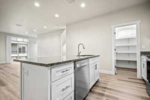 Kitchen with an island with sink, stainless steel dishwasher, light hardwood / wood-style floors, and sink