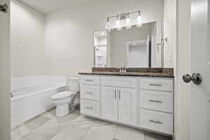 Bathroom featuring vanity, toilet, and a tub