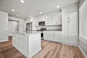 Kitchen featuring white cabinets, light wood-type flooring, and appliances with stainless steel finishes