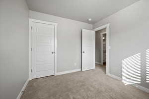 Unfurnished bedroom with light colored carpet and a closet