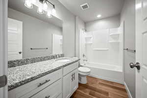 Full bathroom featuring washtub / shower combination, wood-type flooring, vanity, and toilet