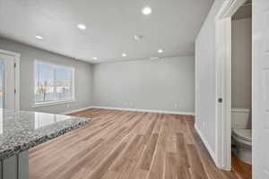 Unfurnished living room featuring a textured ceiling and light hardwood / wood-style flooring